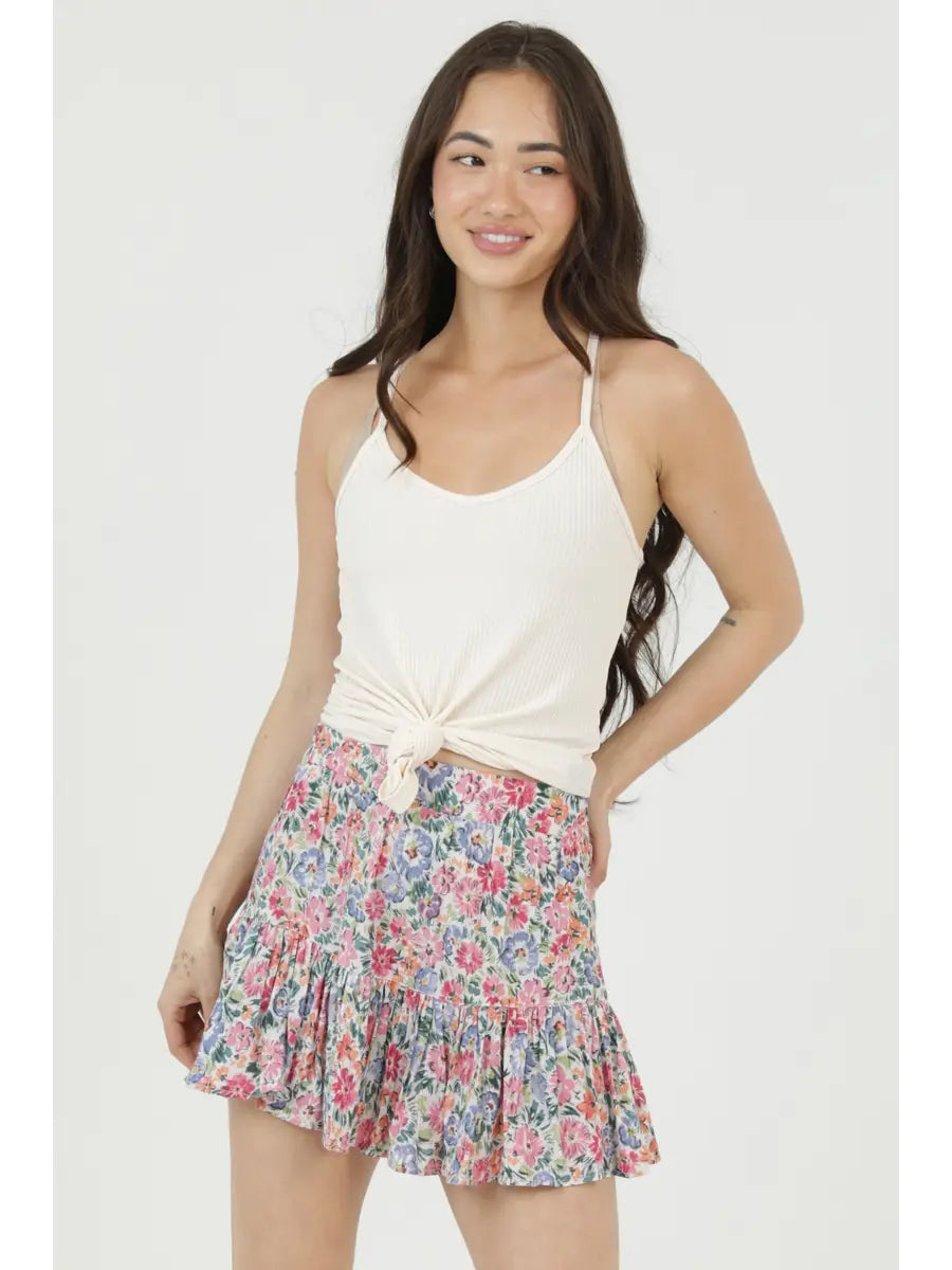 Women's floral print mini skirt with a tiered ruffle hem and flowy silhouette, styled with a fitted tank top.