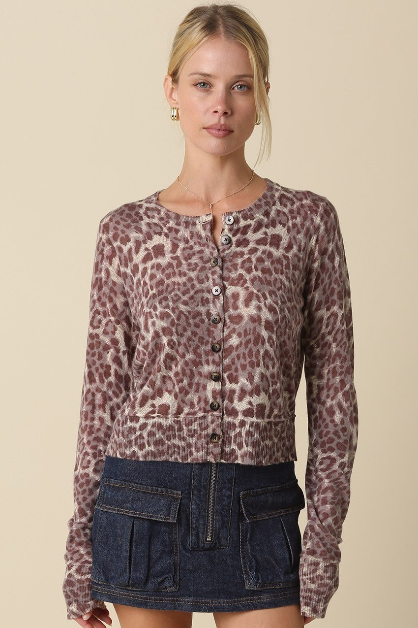 Woman wearing a fitted leopard-print cardigan with a round neckline, button-front closure, and ribbed trim.