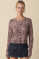 Woman wearing a fitted leopard-print cardigan with a round neckline, button-front closure, and ribbed trim.