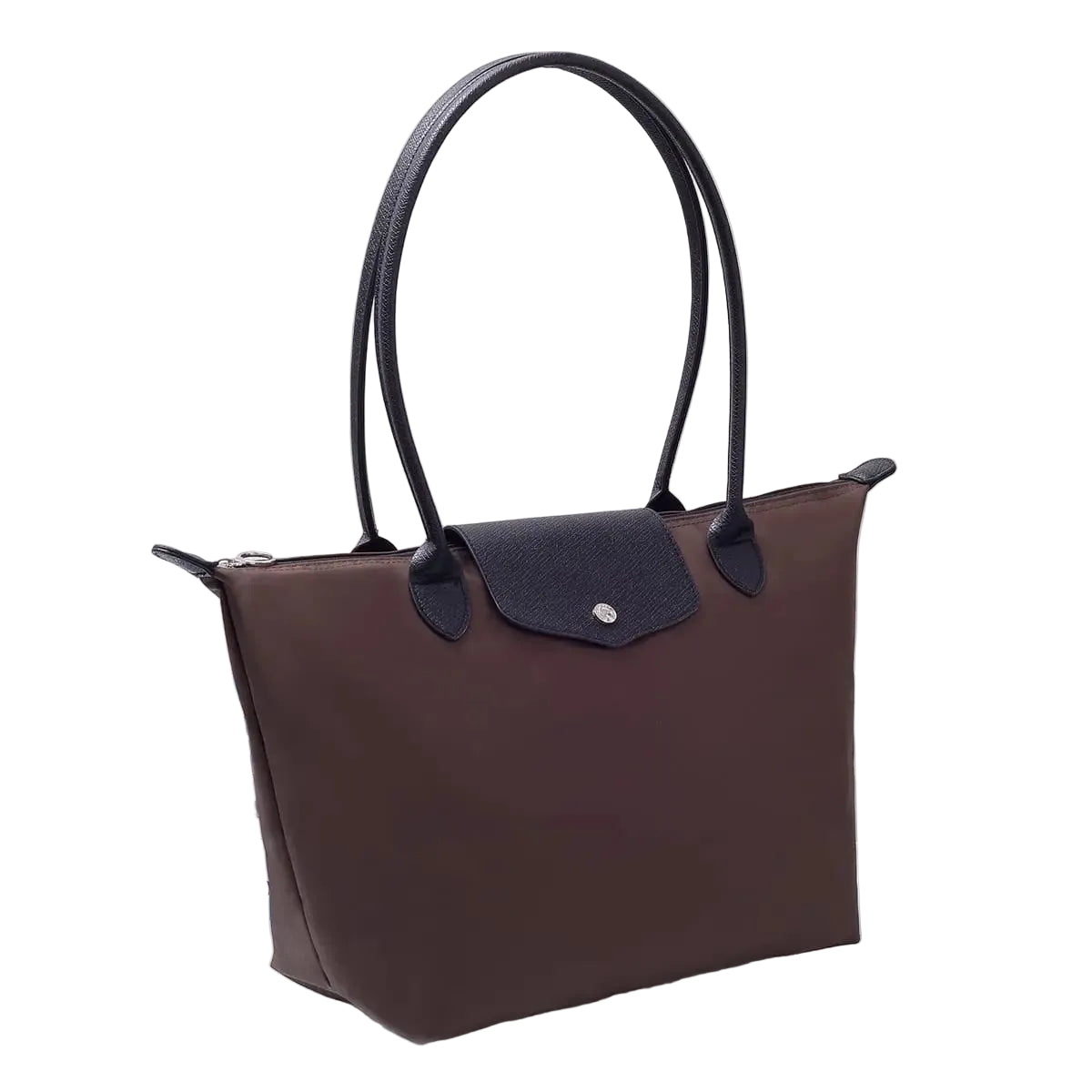 A brown and black leather tote bag with double shoulder straps, displayed on a white table next to a stack of books in front of a white curtain background.