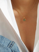 Gold-tone chain necklace with a round pendant charm, styled on a model with a white blouse and denim jacket for a chic, everyday look.