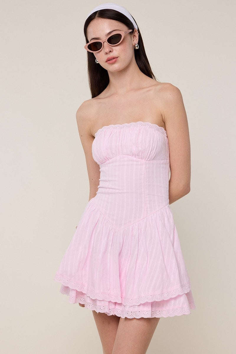 Strapless mini dress with fitted bodice, textured fabric, and tiered flouncy skirt styled with sunglasses