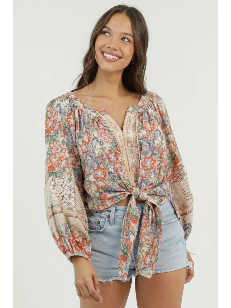 Printed blouse with v-neckline, long sleeves, and front tie detail styled with denim shorts