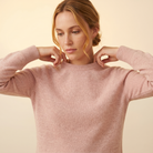 Woman wearing a pink sweater against a beige background
