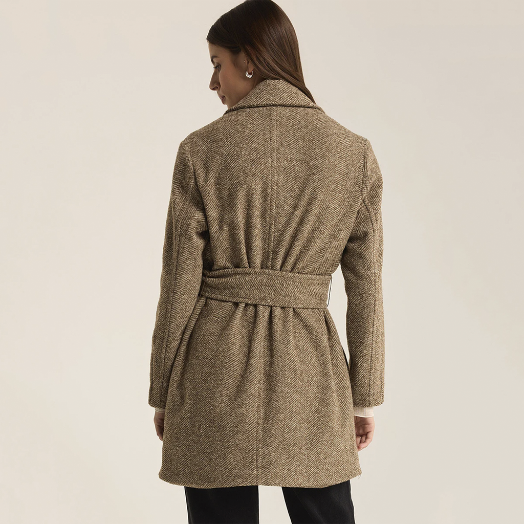 Elevate your wardrobe with the Z Supply Hawthorne Herringbone Coat in Dark Chocolate. Made from midweight fabric, this coat showcases a classic herringbone pattern and is designed with a notch collar, button-front closure, and a belted silhouette. The lined interior and flap pockets combine style and functionality, making it the perfect piece to layer over any outfit for a sophisticated touch.