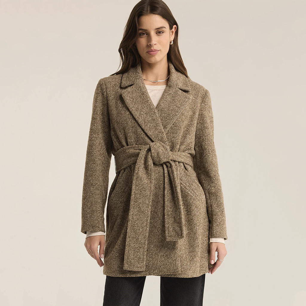 Elevate your wardrobe with the Z Supply Hawthorne Herringbone Coat in Dark Chocolate. Made from midweight fabric, this coat showcases a classic herringbone pattern and is designed with a notch collar, button-front closure, and a belted silhouette. The lined interior and flap pockets combine style and functionality, making it the perfect piece to layer over any outfit for a sophisticated touch.