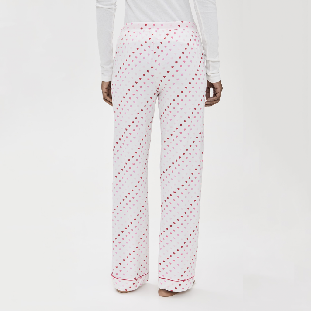 Indulge in comfort and charm with this luxe pajama set, featuring soft pink hearts and buttery fabric. The button-down top with piping details and loose-leg pants with an elastic waist offer the perfect combination of relaxation and style.