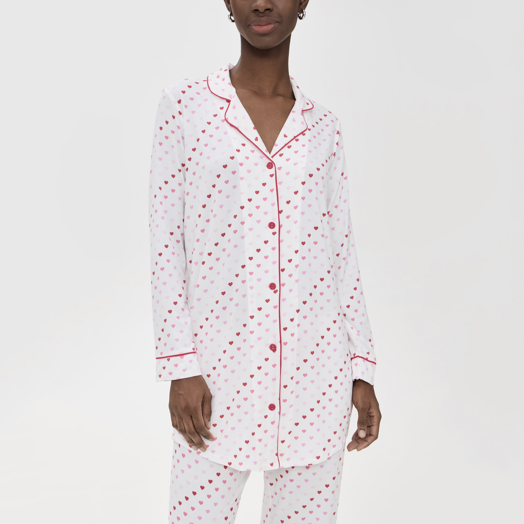 This sweet ivory pajama top features playful red heart prints, a classic collar, and a chest pocket for the perfect blend of comfort and style. Ideal for cozy nights or lounging in style!