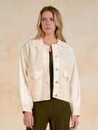 Woman wearing a front-facing mixed-media jacket with front pockets.