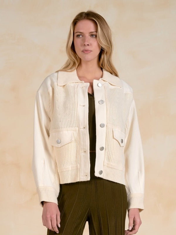 Woman wearing a front-facing mixed-media jacket with front pockets.
