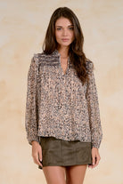 Printed long-sleeve blouse with smocked shoulder detailing, ruffled neckline, and relaxed fit.