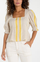 Square neckline top with puff sleeves and open back tie detail styled with fitted pants