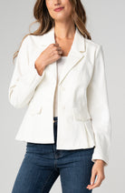 Tailored ivory peplum blazer with structured fit, lapel collar, and button-front closure styled with jeans