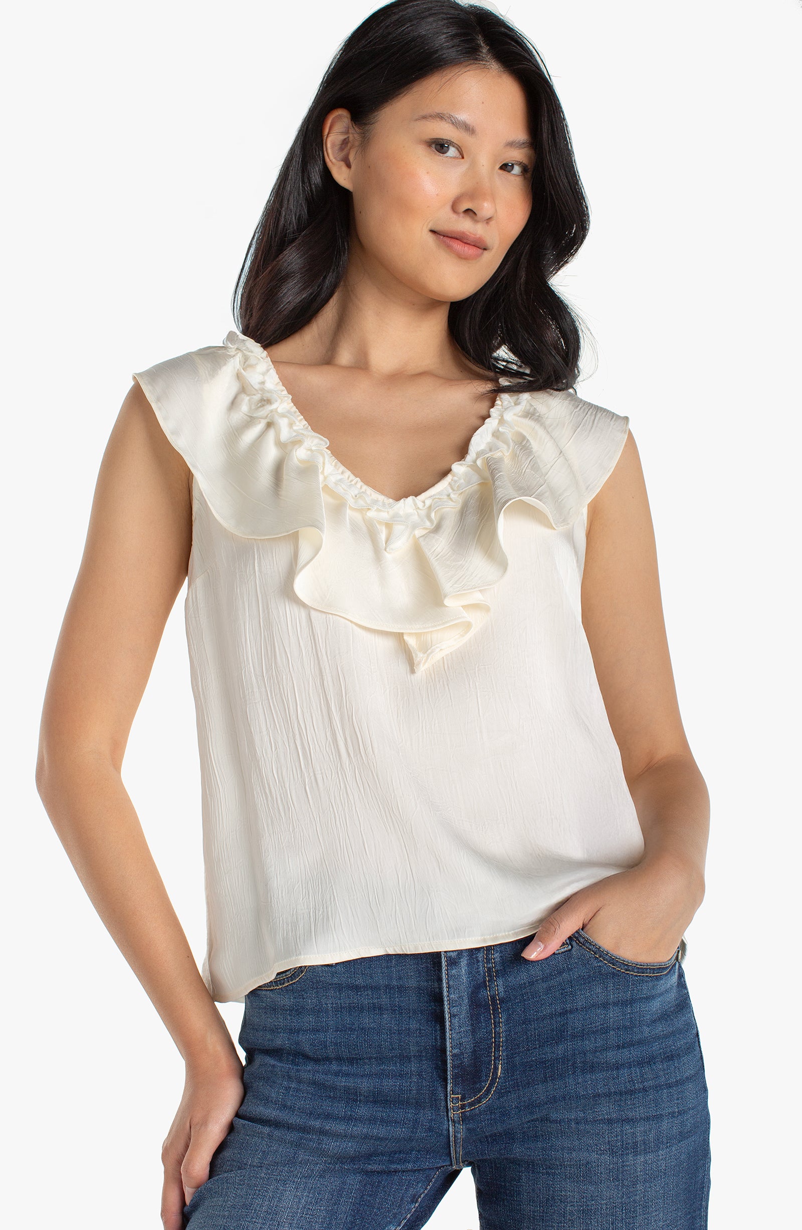 Ivory Sleeveless top with ruffled neckline and flowy fit styled with jeans