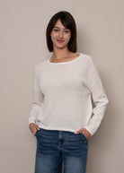 Model wearing a lightweight knit sweater with a boat neckline, relaxed fit, and long sleeves.