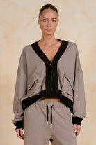 Model wearing a cropped zip-up jacket with contrast trim, utility-inspired flap pockets, and a relaxed fit, styled with matching drawstring joggers against a neutral studio background.