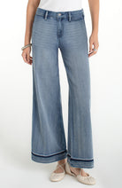 Woman wearing high rise wide leg cropped denim jeans with subtle hem detail styled with flats