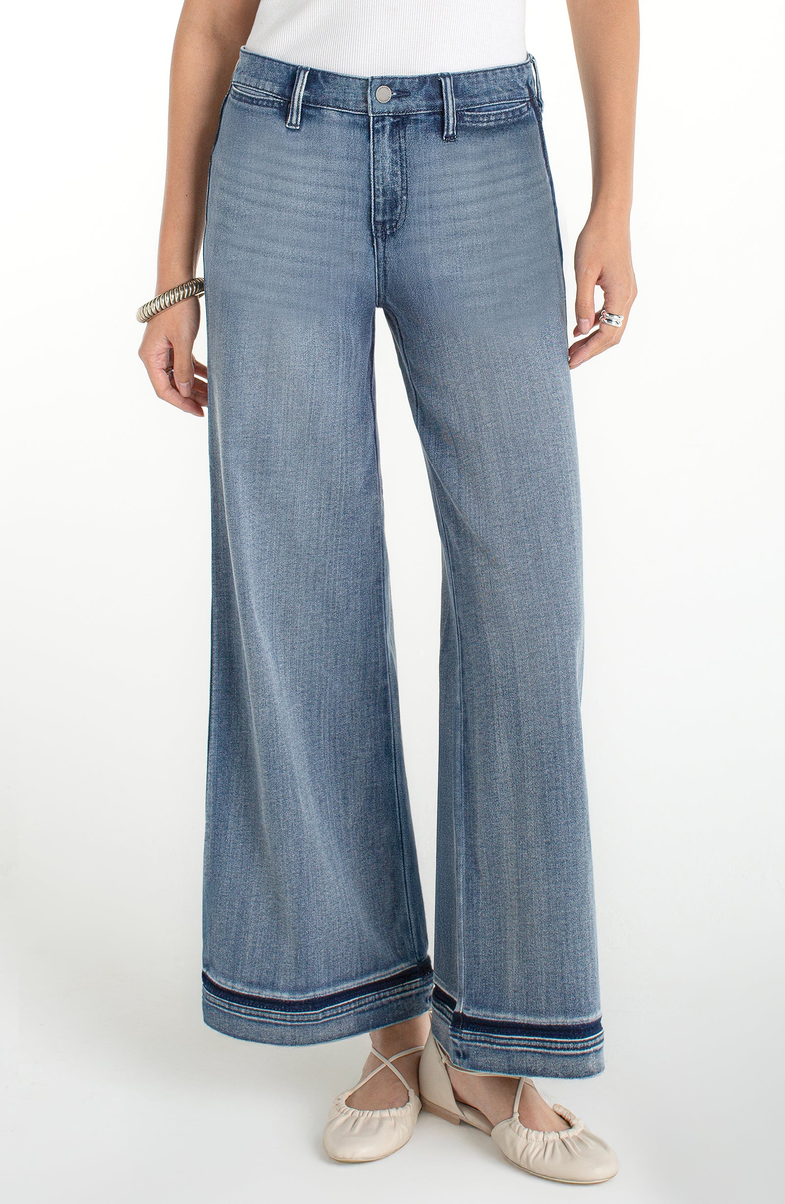 Woman wearing high rise wide leg cropped denim jeans with subtle hem detail styled with flats