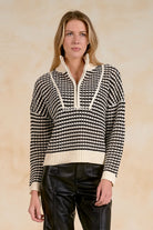 Model wearing a striped half-zip knit sweater with contrast ribbed trim and a relaxed fit, styled with black faux leather pants against a neutral studio background.