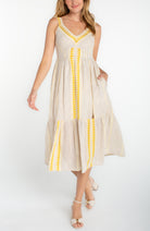 Sleeveless midi dress with a v-neckline, fitted bodice, and tiered skirt styled with heeled sandals