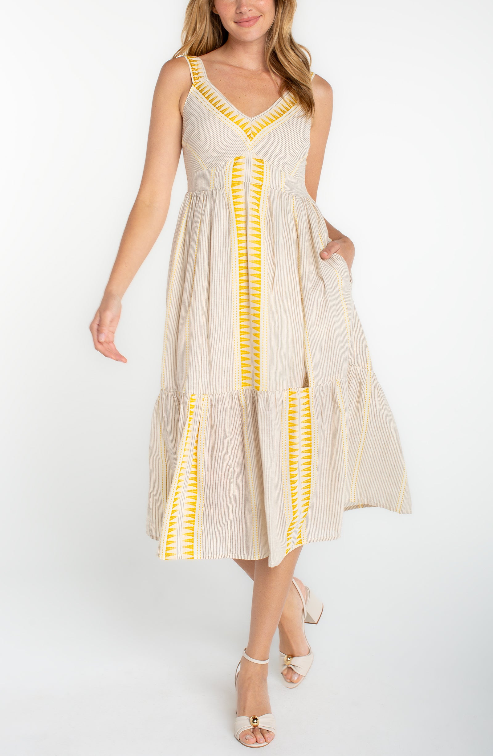 Sleeveless midi dress with a v-neckline, fitted bodice, and tiered skirt styled with heeled sandals