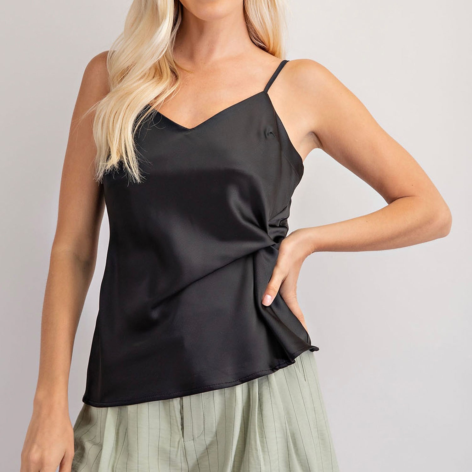 V-Neck Front Knot Cami. Radiate luxe vibes wearing this twist knot v-neck cami! In a flattering design featuring a knot front, V neckline and black satin fabric, this is a new season essential! Finish the look with killer heels and cute bottoms for the perfect party ready style! 
