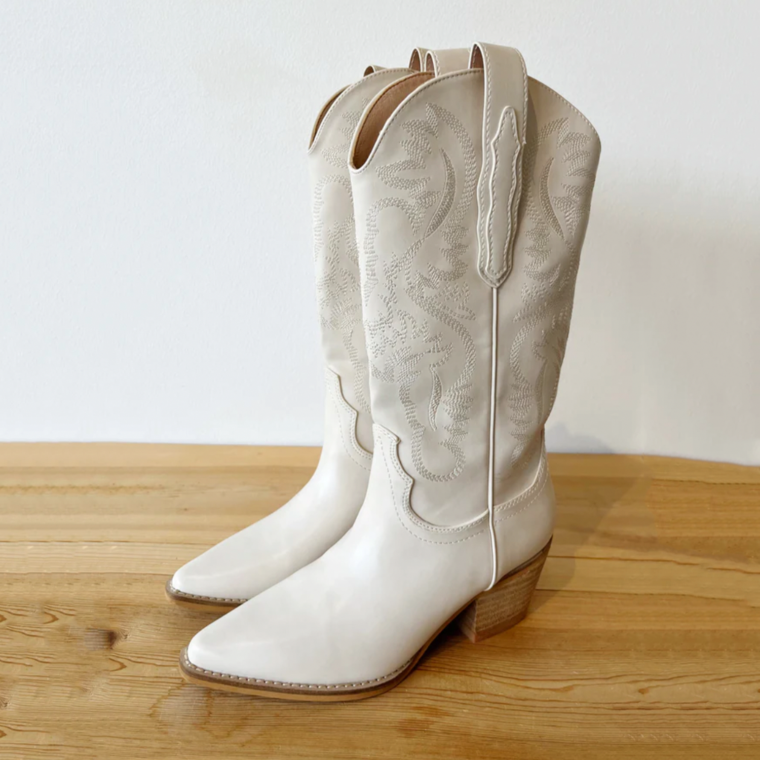 Cowboy Boot. Mid-calf high white cowboy boots. Pull-on styleCowboy Boot. An outlaw of the Wild West. This boot is perfect with a western silhouette and traditional snip. Fashioned with decorative stitching and pull straps, this low heeled boot is ready for any outfit